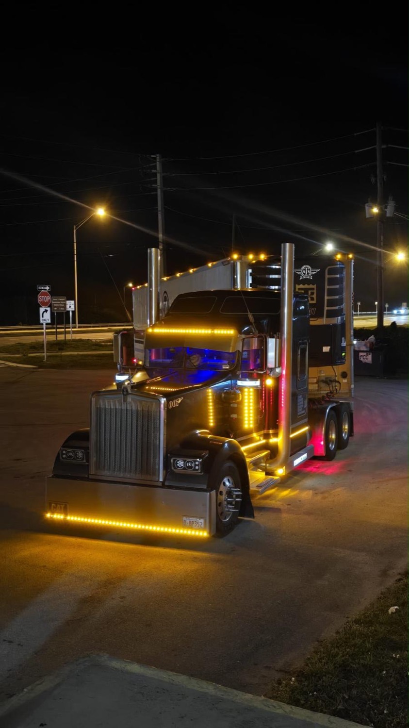 Kenworth lit with amber LED lights at night with a CAT bumper